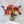 Load image into Gallery viewer, A vibrant floral arrangement featuring a variety of bold blooms including peonies, garden roses, ranunculus, tulips, delphinium, scabiosa, lisianthus, and sweet pea in a ceramic compote vase.
